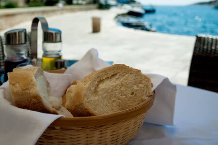 The bread and olive oil is standing on the table next to the ocean.の写真素材