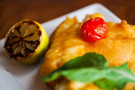 Plate of fish with cherry and lemon on the side.の写真素材