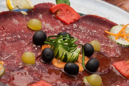 A salami plate with white and black grapes.の写真素材