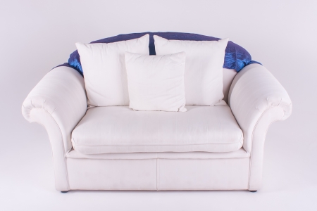 A huge couch with three cushions and blue throw.の写真素材