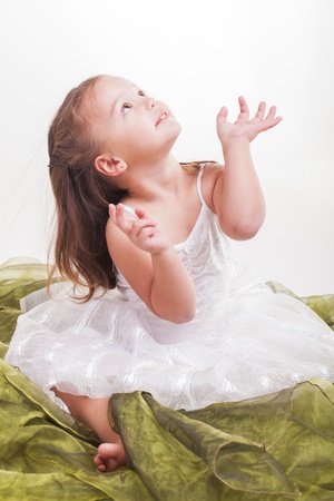 Sitting on the green organza, she is intrigued with the sky.の写真素材