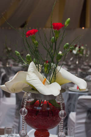 A centre piece on the stage with flowers, glass and red colourance.の写真素材