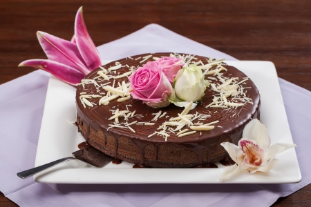 A big chocolate cake with sauce and some flowers.の写真素材