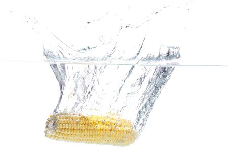 A peeled corn being washed in water.の写真素材