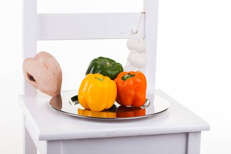 Peppers in a silver plate on a chair with garlic on the side.の写真素材