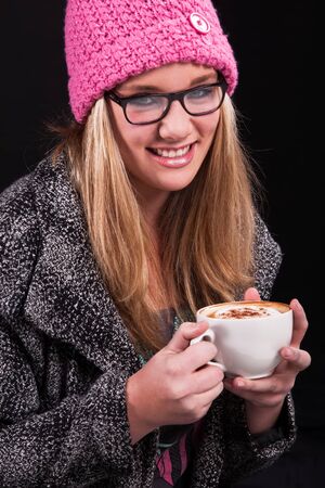 Warm jacket, warm coffee, pink beany and black glasses.の写真素材