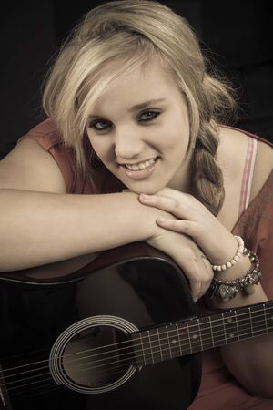 A young country girl with her guitar in the studio.の写真素材