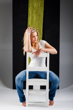 The girl is dressed in a blue jean, white shirt and a bad look.の写真素材