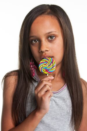 The young girl is eating a lollipop with a lot of different colours.の写真素材