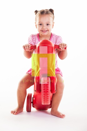 A young girl dressed in pink shorts and shirt on a red bike.の写真素材