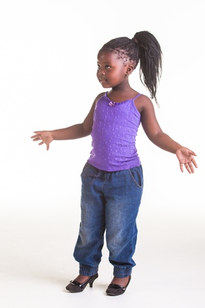 A little African girl dressed in purple blouse, blue jeans and black heels.の写真素材