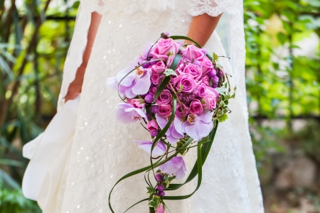 The bride in her wedding dress with her beautiful bouquet filled with pink roses and orchads.の写真素材