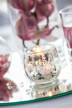 Center piece consist out of dark pink flowers and candles in a bowl.の写真素材