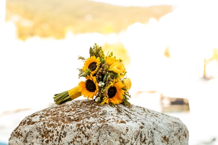 A bouquet  that cosists of sunflowers and yellow roses on a rock.の写真素材