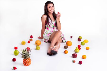 A young model in the studio on the floor with different fruits の写真素材