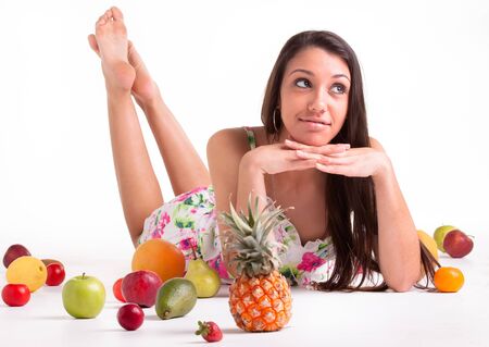 A young model in the studio on the floor with different fruits の写真素材