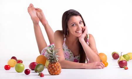 A young model in the studio on the floor with different fruits の写真素材