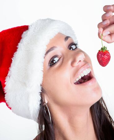 A young female model with a red christmas hoodie and strawberry in the hand の写真素材