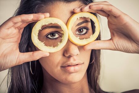 A female model look through lemon skins with a serious faceの写真素材