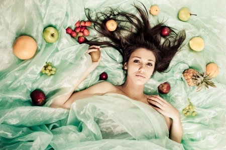 A young lady on green organza with fruit の写真素材