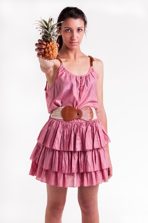 A young teenage model with a pineapple in her right hand の写真素材
