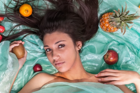 A young female caucasion model on green organza with fruitsの写真素材