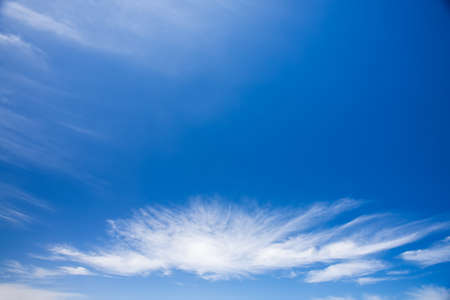 A small white acspanding cloud in clear blue skies の写真素材