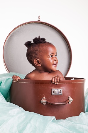 A little African girl in a hat case on a light turqoise organza.の写真素材