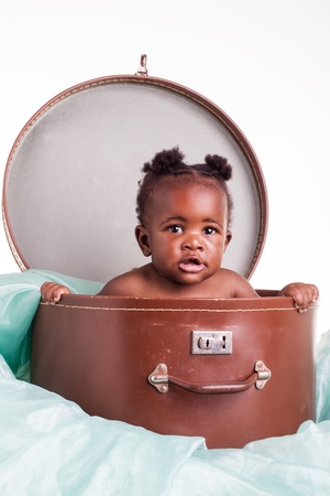 A little African girl in a hat case on a light turqoise organza.の写真素材