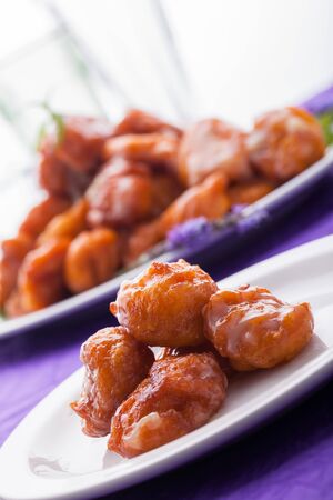 A big plate of freshly made saucy and golden pumpkin fritters with a smaller plate as well.の写真素材