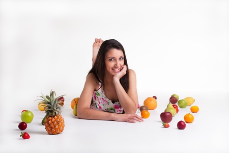 A young model in the studio on the floor with different fruits.の写真素材