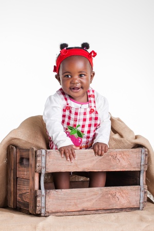 A small African girl dressed as a farm girl in a cradle.の写真素材