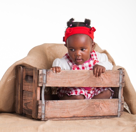 A small African girl dressed as a farm girl in a cradle.の写真素材