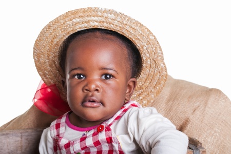 A small African girl dressed as a farm girl in a cradle.の写真素材