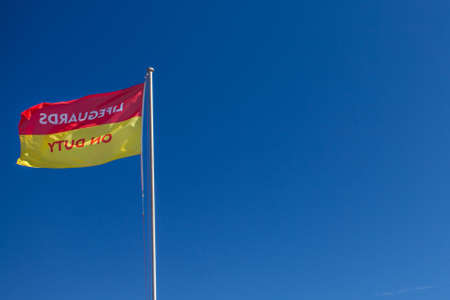 A flag waving around in clear bue sky, letting you know safety is nearby.の写真素材