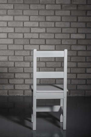 A slim white chair is standing towards the wall.の写真素材