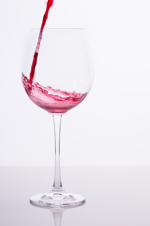 Red wine is being poured into a big wine glass.の写真素材