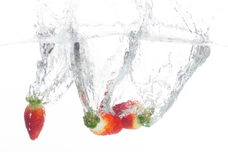 Strawberries are thrown into a bowl of fresh water.の写真素材