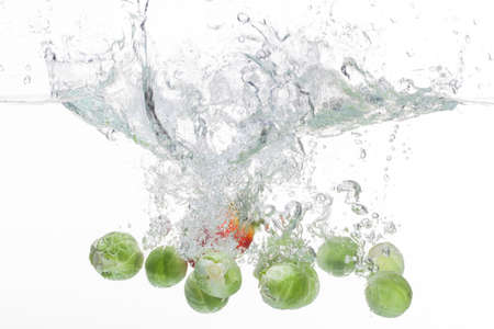 Small cabbages and a strawberry being cleaned in water.の写真素材