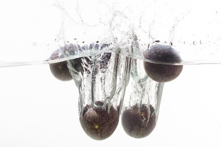 Four granadillas in a bowl of water.の写真素材