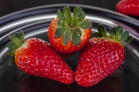 Three strawberries laying on a glass plate.の写真素材