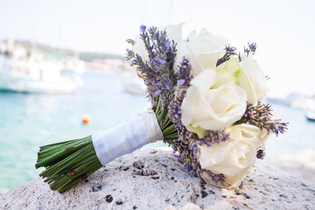 A beautiful bouquet of white roses laying on a rock by the ocean.の写真素材
