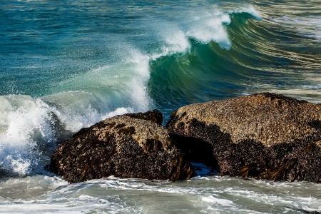 Rocks in the ocean about to be crushed by a wave.の写真素材