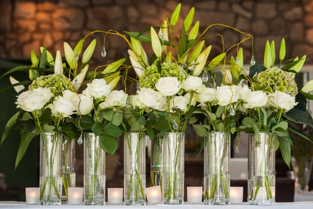 A whole bunch of roses in huge vases on a table with lillies.の写真素材