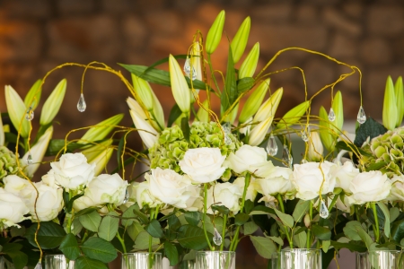 A whole bunch of roses in huge vases on a table with lillies.の写真素材