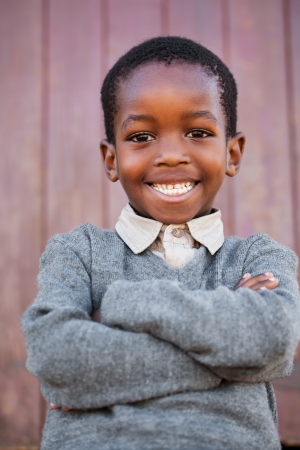 A friendly school boy with crossed arms before the classroom の写真素材