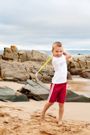 A blond little boy are being photographed on the beach while playing golf..の写真素材