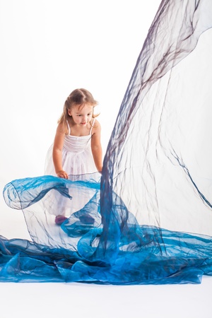 A little girl sitting on a piece of green organza.の写真素材
