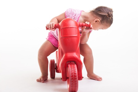 A toddler with her three wheel bike, very consernd about the condition.の写真素材