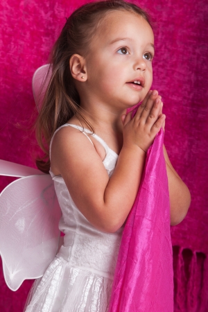 A girl in a white fairy outfit with pink backdrop.の写真素材